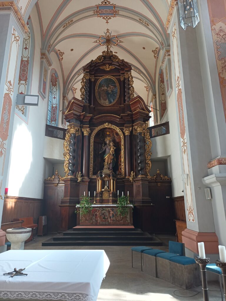 Blick auf den Hochaltar mit aus Nussbaumholz mit der Skulptur des Heiligen Josef. Dieser hält das Christuskind auf dem Arm. 