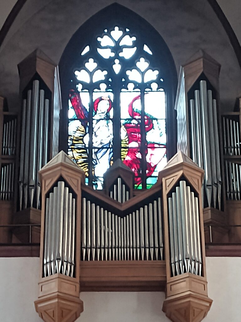 Orgel der Liebfrauenkirche in Koblenz mit Blick auf das kunstvolle Fenster dahinter.