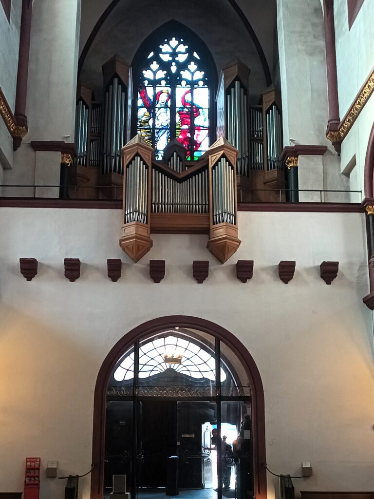 Westempore der Liebfrauenkirche in Koblenz mit Orgel und gotischem Fenster im Hintergrund.