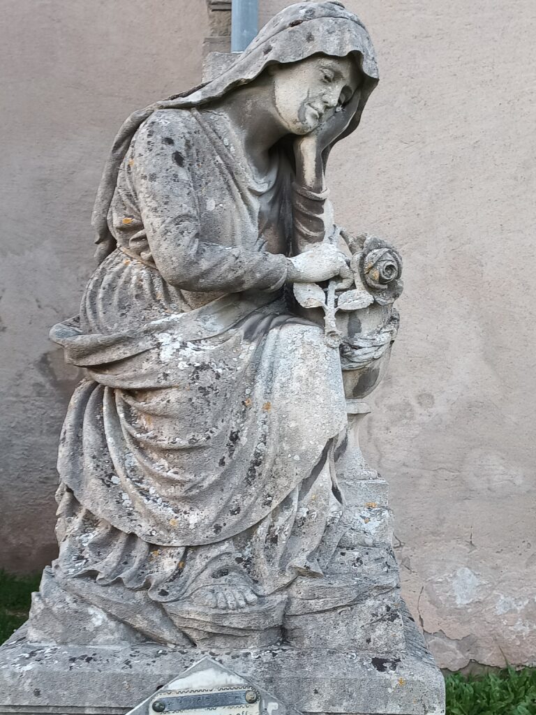 Eine trauernde Frau mit Rose – kunstvolle Details eines historischen Grabsteins der Église St Rémy.