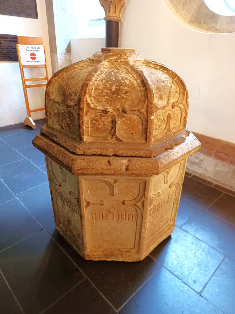 Der historische Blutbrunnen in der Kirche Sankt Andreas, Köln, mit gotischer Ornamentik und sichtbaren Altersspuren.