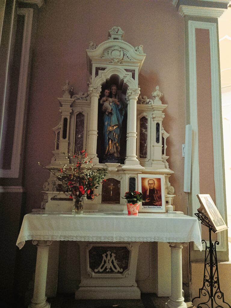 Seitenaltar der Kirche mit Marienstatue, Jesuskind und Bild des Heiligen Maximilian Kolbe