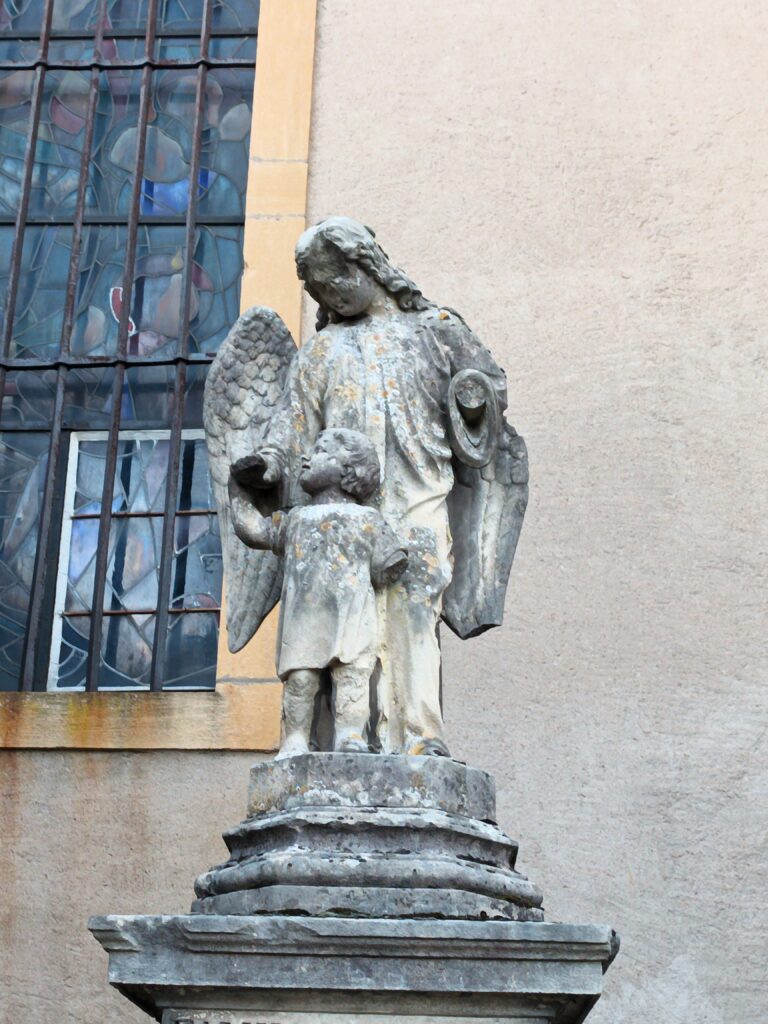 Eine Engelstatue mit Kind auf einem Grabstein – ein Symbol des Schutzes und der Hoffnung.