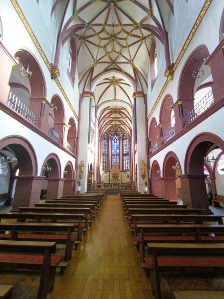 Innenansicht des Langschiffs der Liebfrauenkirche mit romanischen Bögen und Kreuzrippengewölbe.